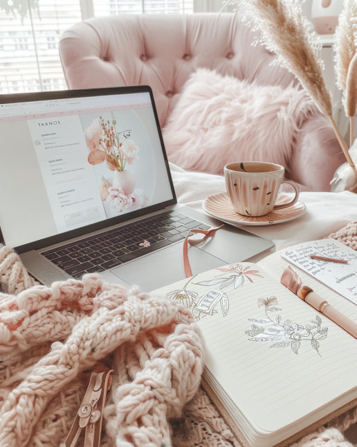 Cozy workspace with open laptop showing planning blog. Planner, tea cup, and doodle notebook on desk.